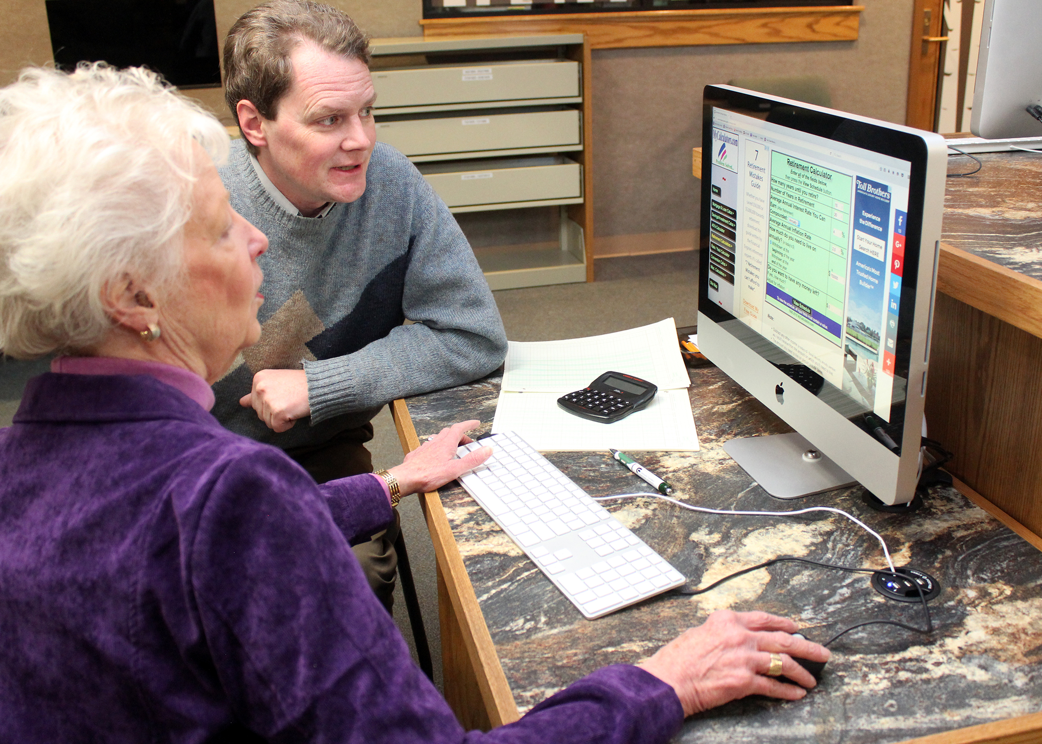 man and woman at desk looking at computer screen