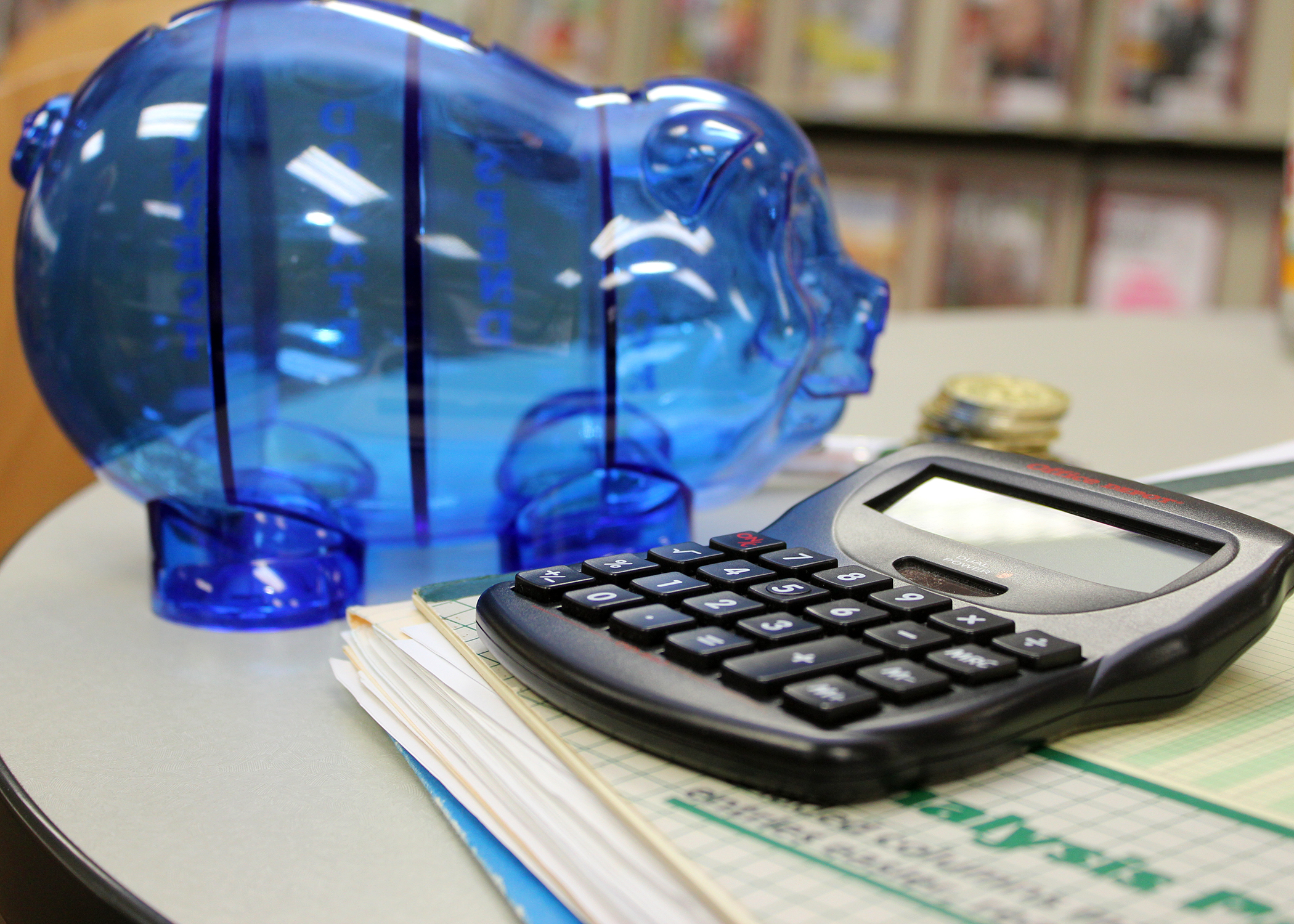 blue piggy bank next to black desk calculator