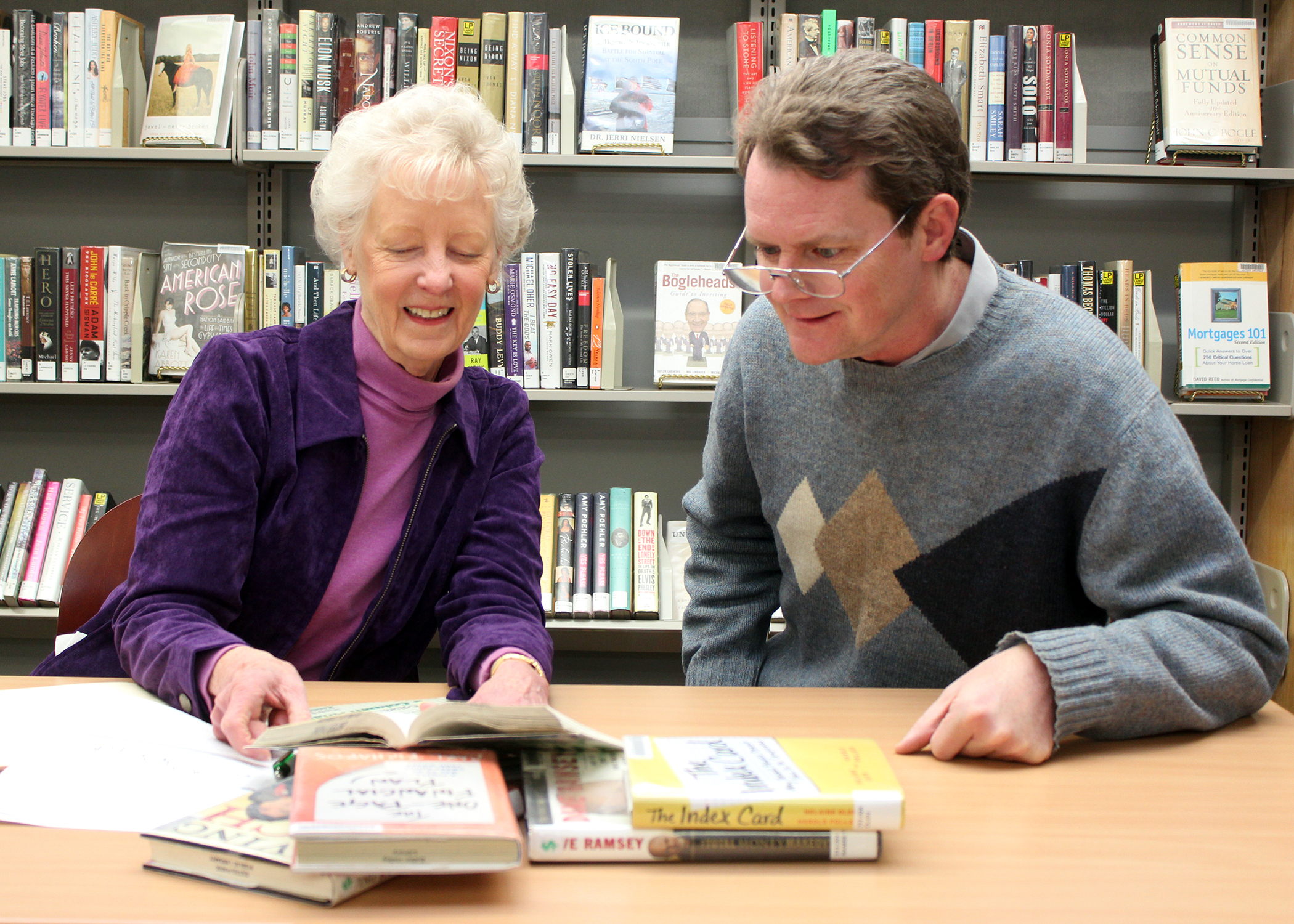 man and woman at a desk looking at books