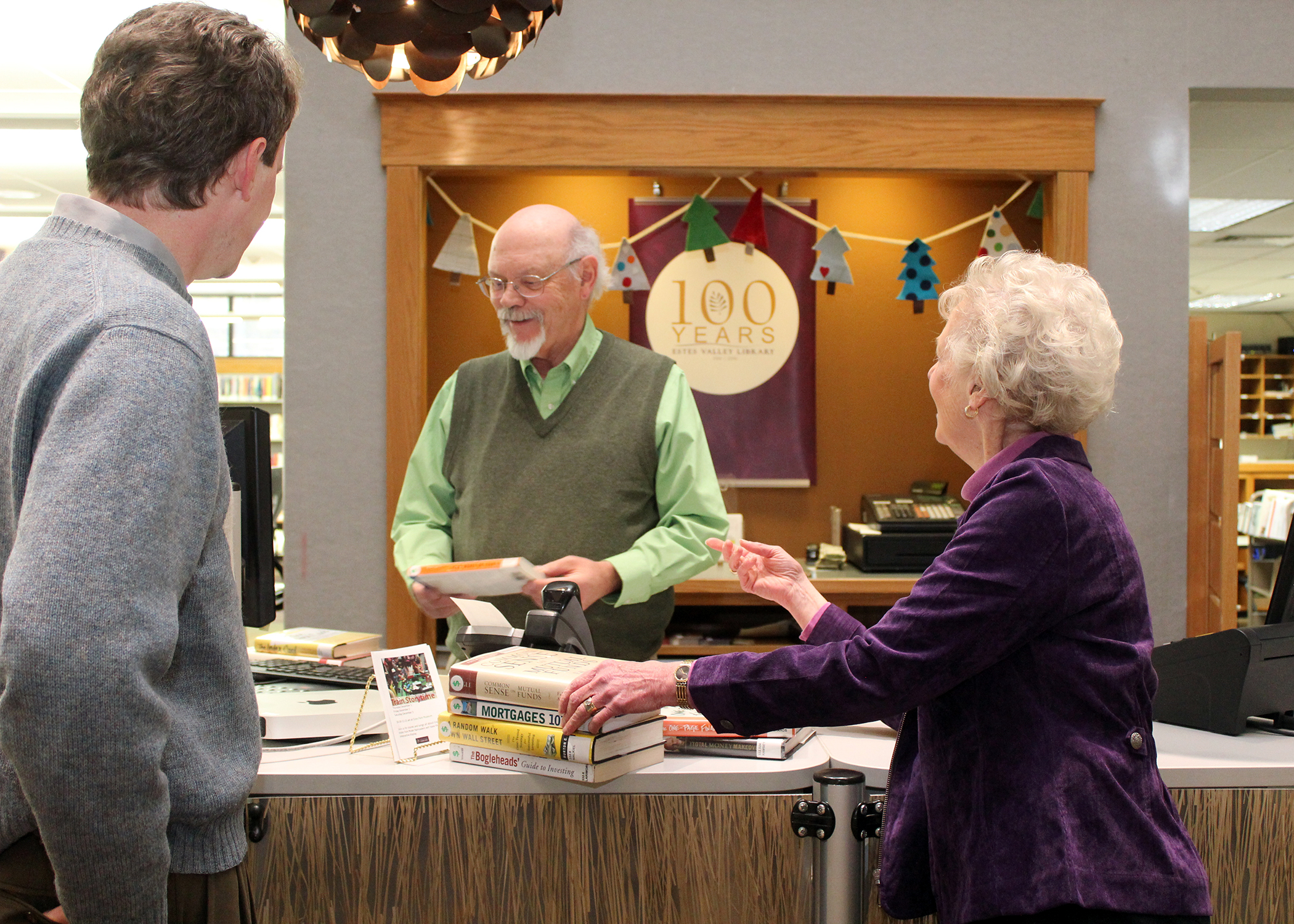 man and woman checking out books from librarian at desk